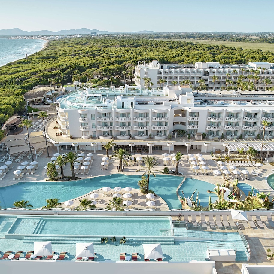 A resort with multiple swimming pools, a beach, and lush greenery.