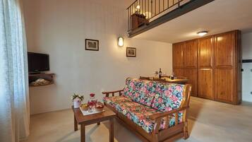 A living room with a wooden sofa, a coffee table, a TV on a shelf, wooden cabinets, and a staircase.