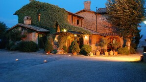 A rustic stone house with ivy-covered walls, a gravel driveway, and outdoor lighting.
