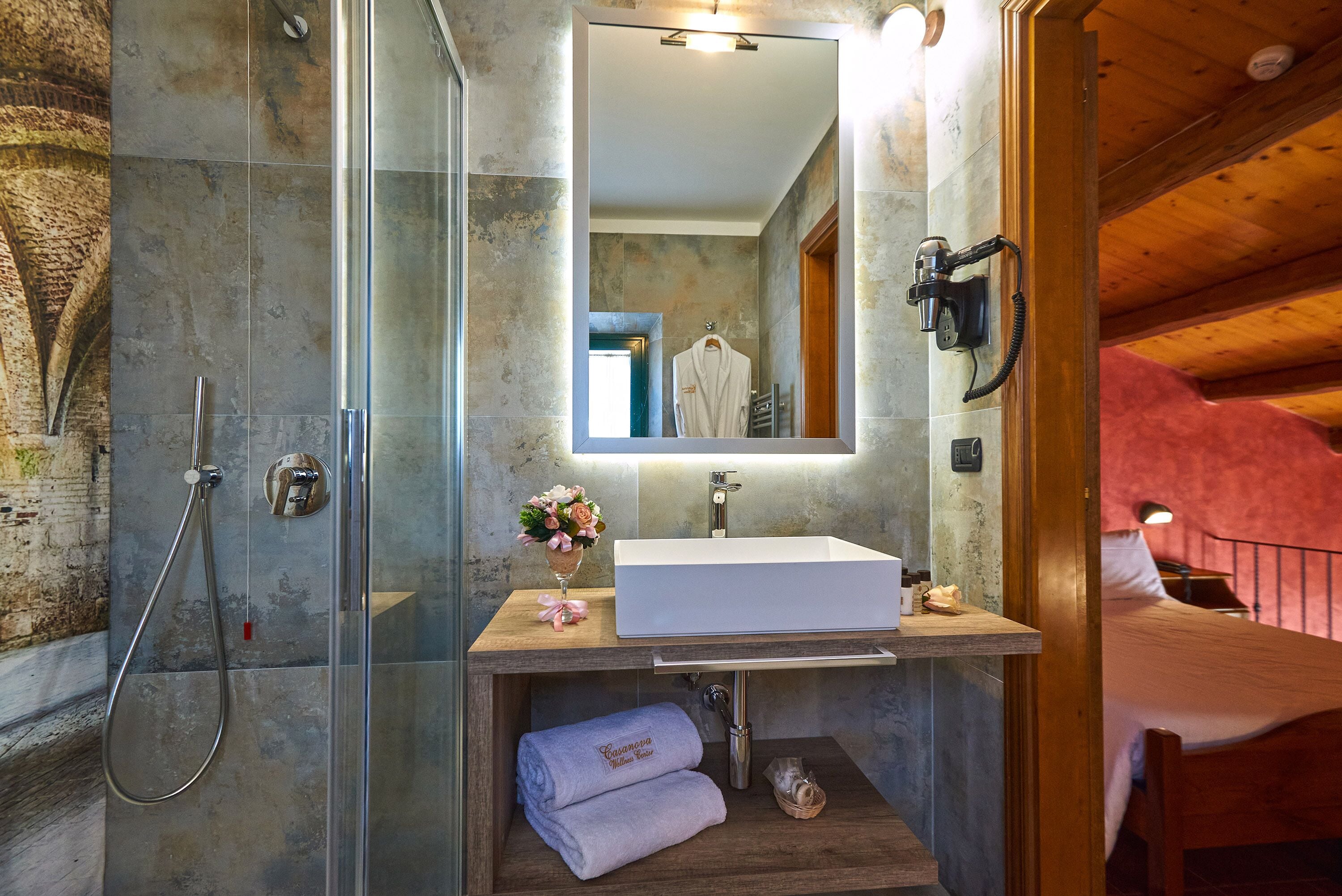 A modern bathroom with a glass-enclosed shower, a white sink, and a wooden vanity.