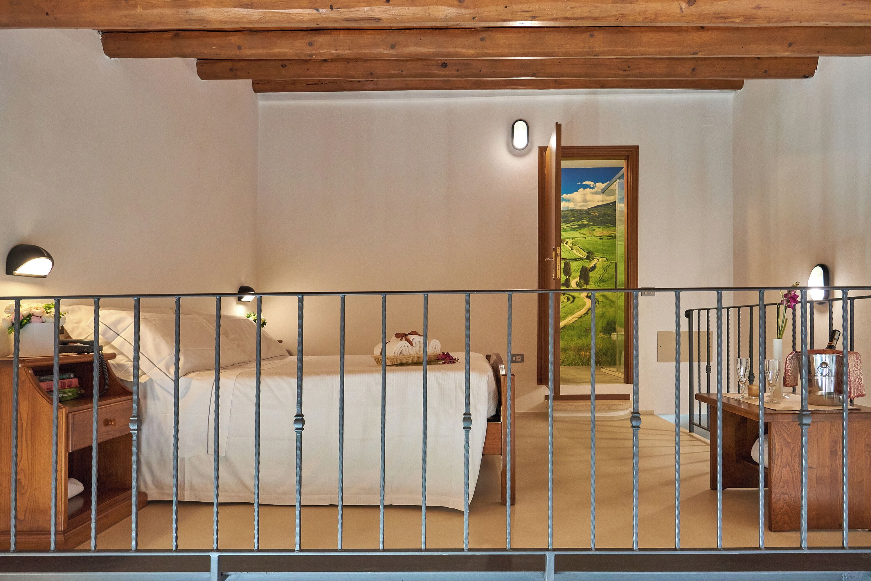 A bedroom with a bed, bedside table, and a painting of a landscape.