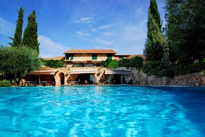 Ein Pool mit einem Steinhaus im Hintergrund.