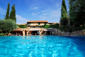 Uma piscina com um edifício de pedra ao fundo.