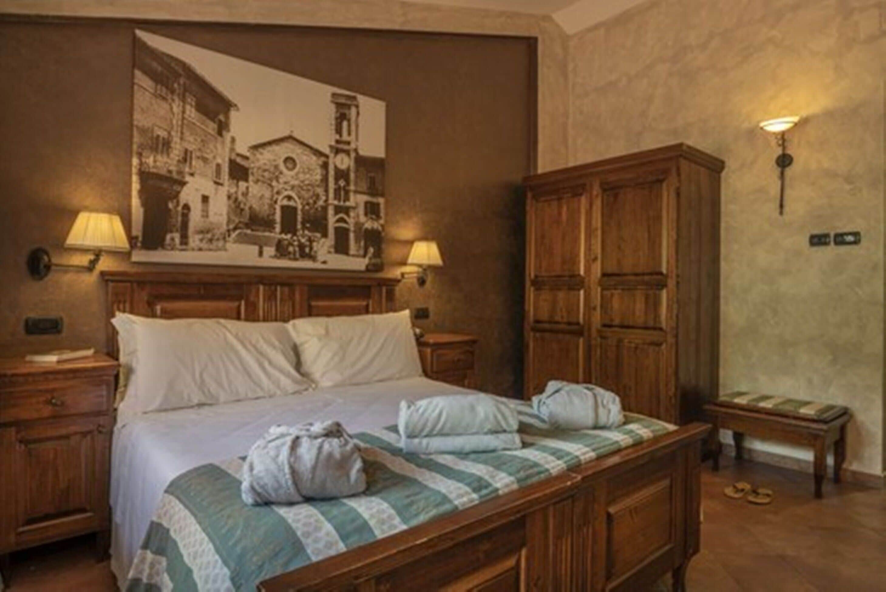 Une chambre à coucher de style traditionnel, avec un grand lit, une armoire en bois et une lampe fixée au mur.