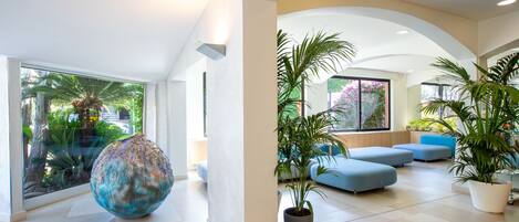 A spacious indoor area with a large glass window, a decorative spherical object, and several potted plants.