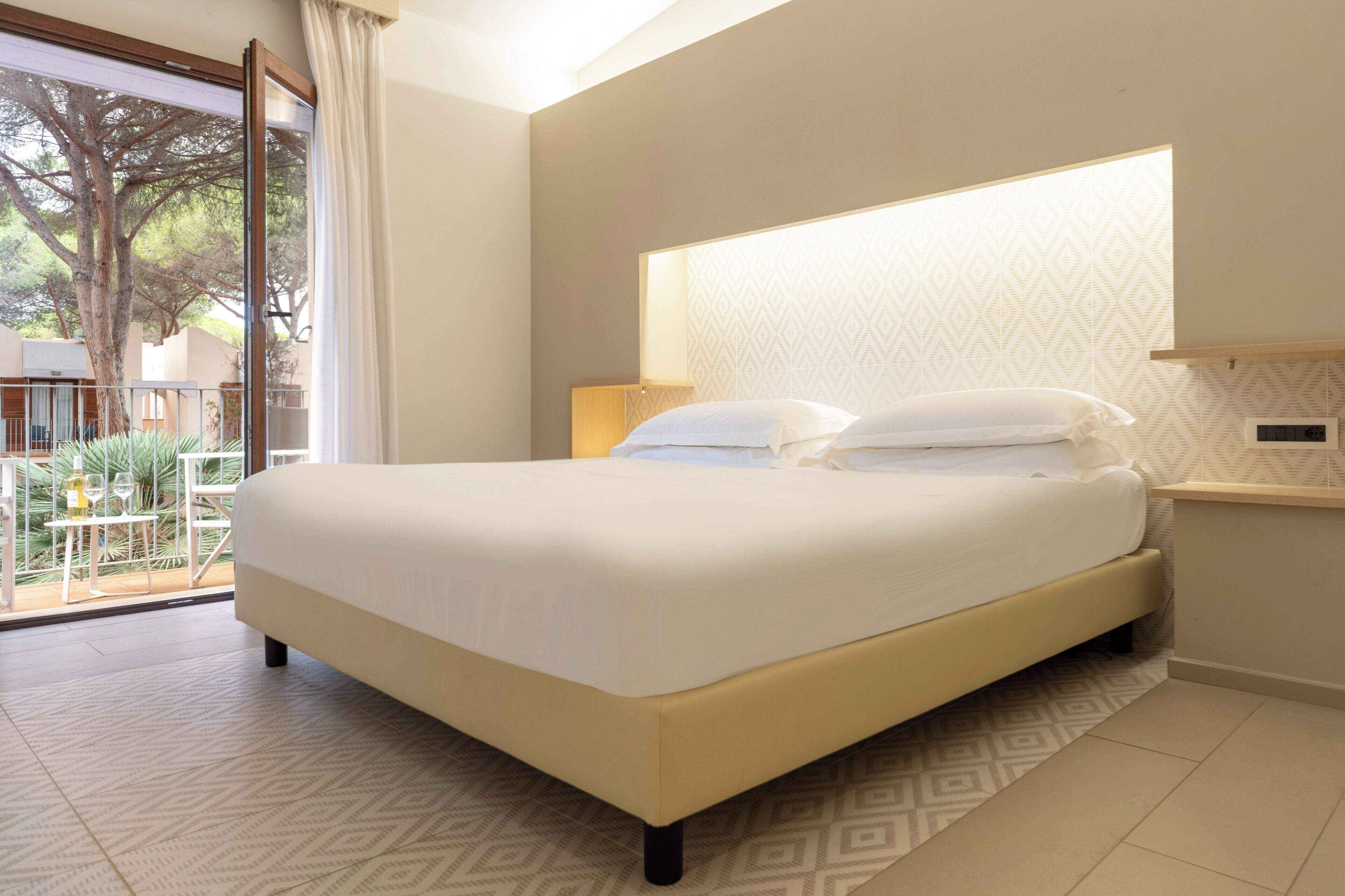 Een slaapkamer met een groot bed, een nachtkastje, een lamp en uitzicht op de omgeving.