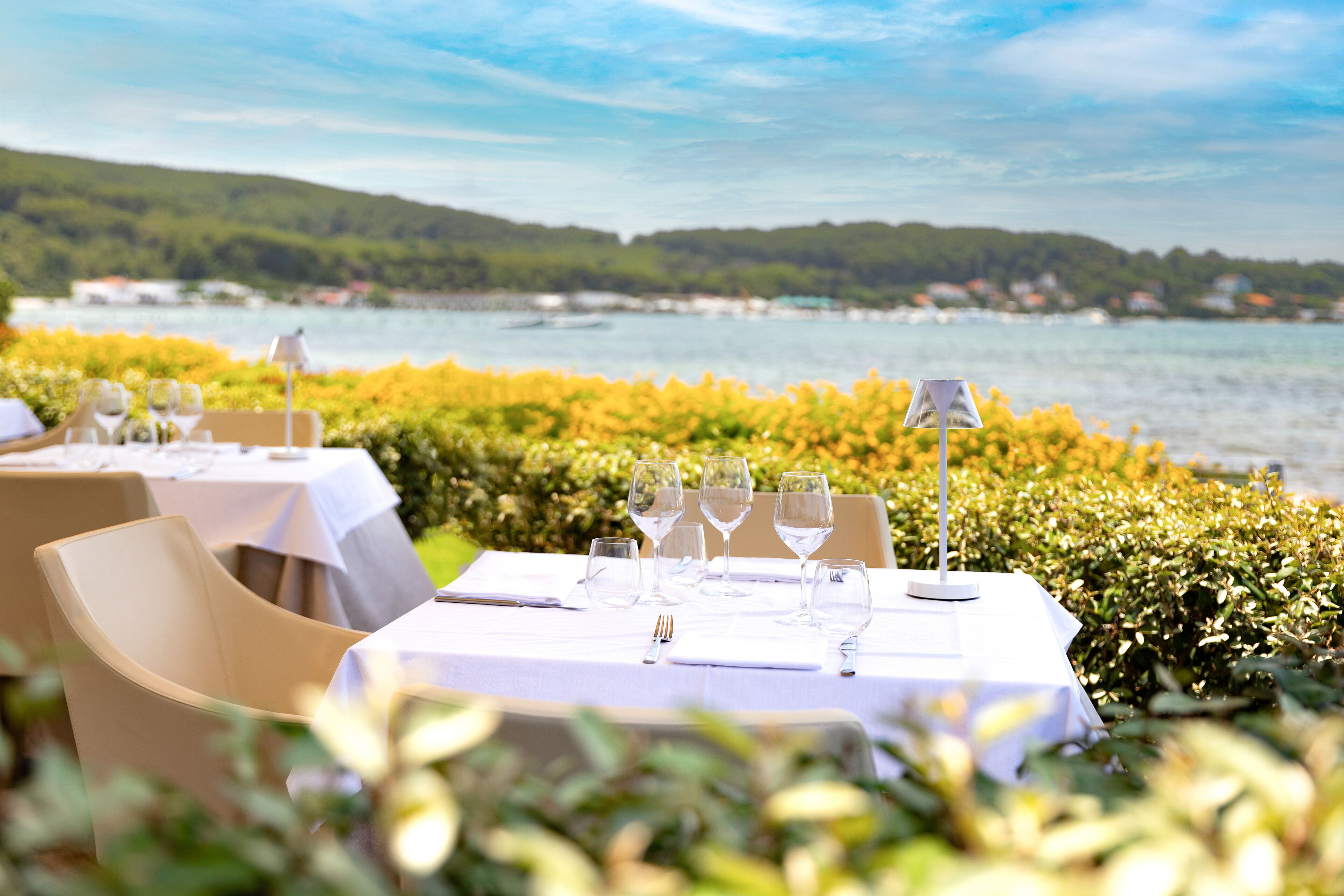A table set for dining with a view of a lake and hills.