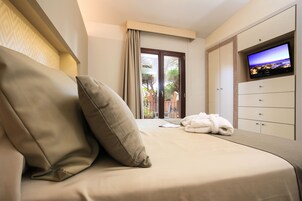 Habitación de hotel con cama, televisor, armario y vistas al exterior.