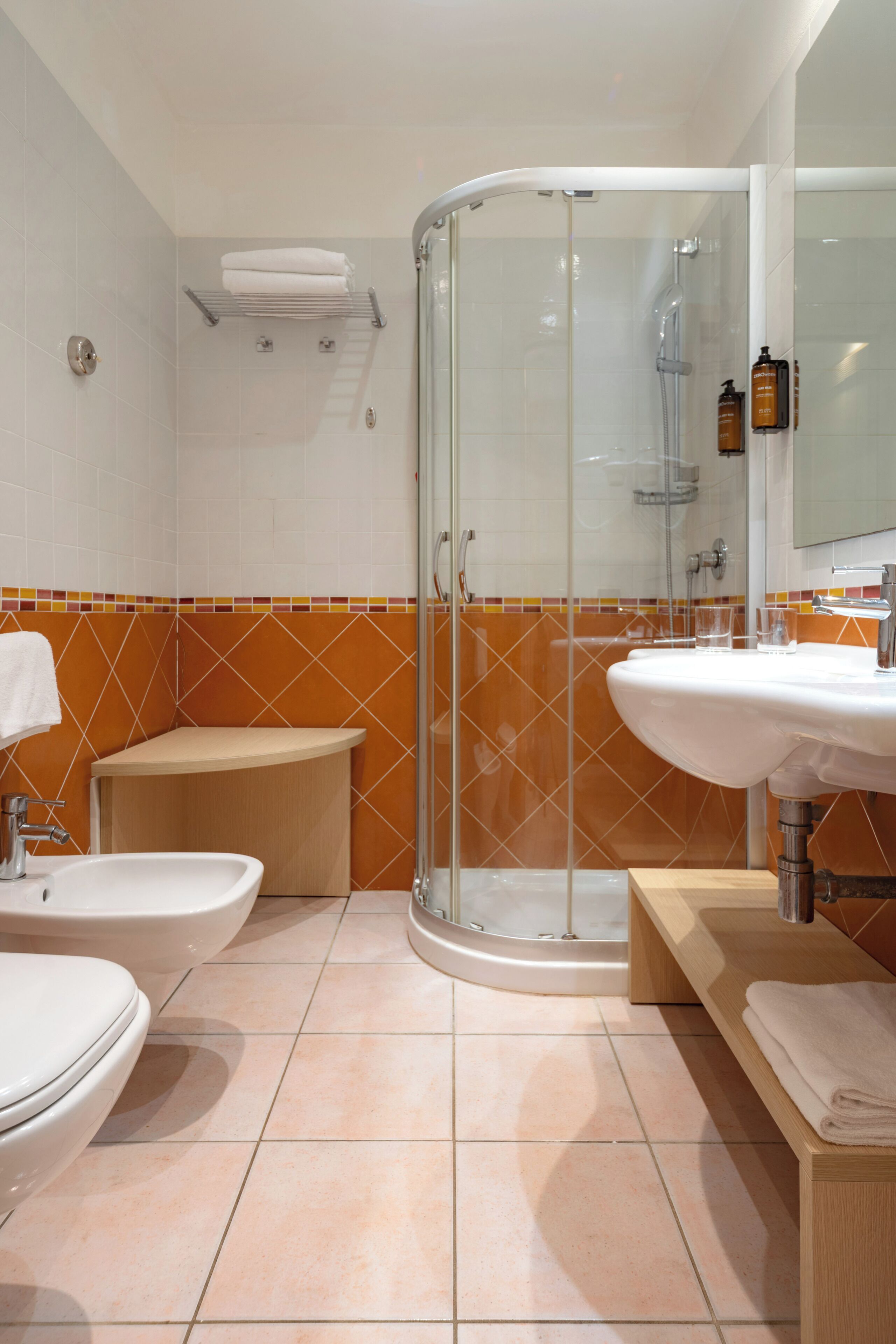 A modern bathroom with a glass shower enclosure, a sink, a bidet, and a toilet.