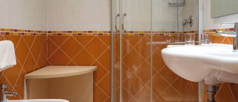A modern bathroom with a glass shower enclosure, a sink, a bidet, and a toilet.