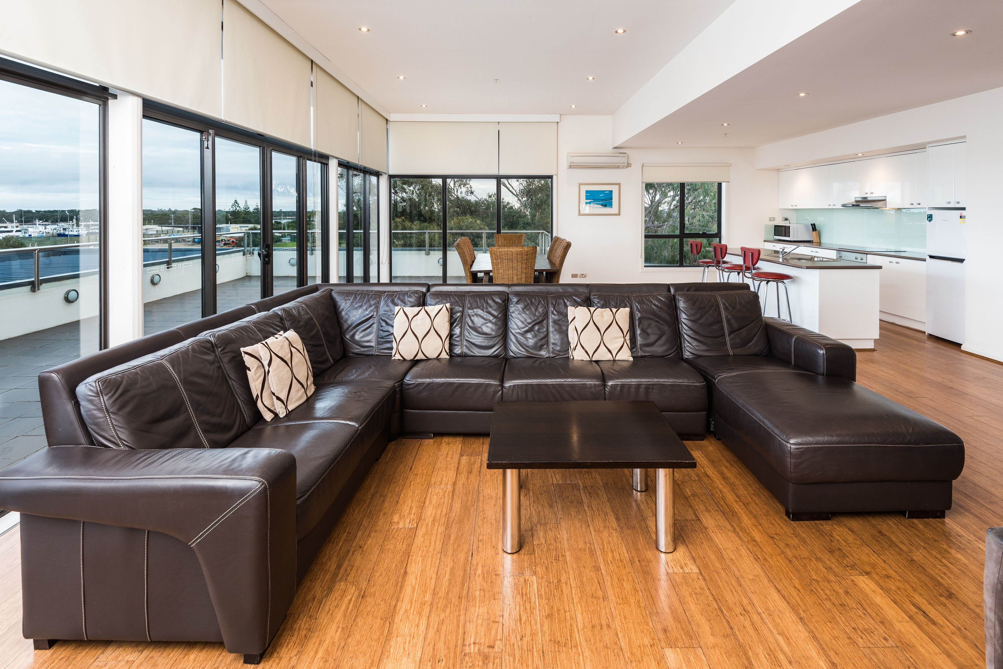 A modern living room with a large L-shaped sectional sofa, a small coffee table, and a dining area with a table and chairs.