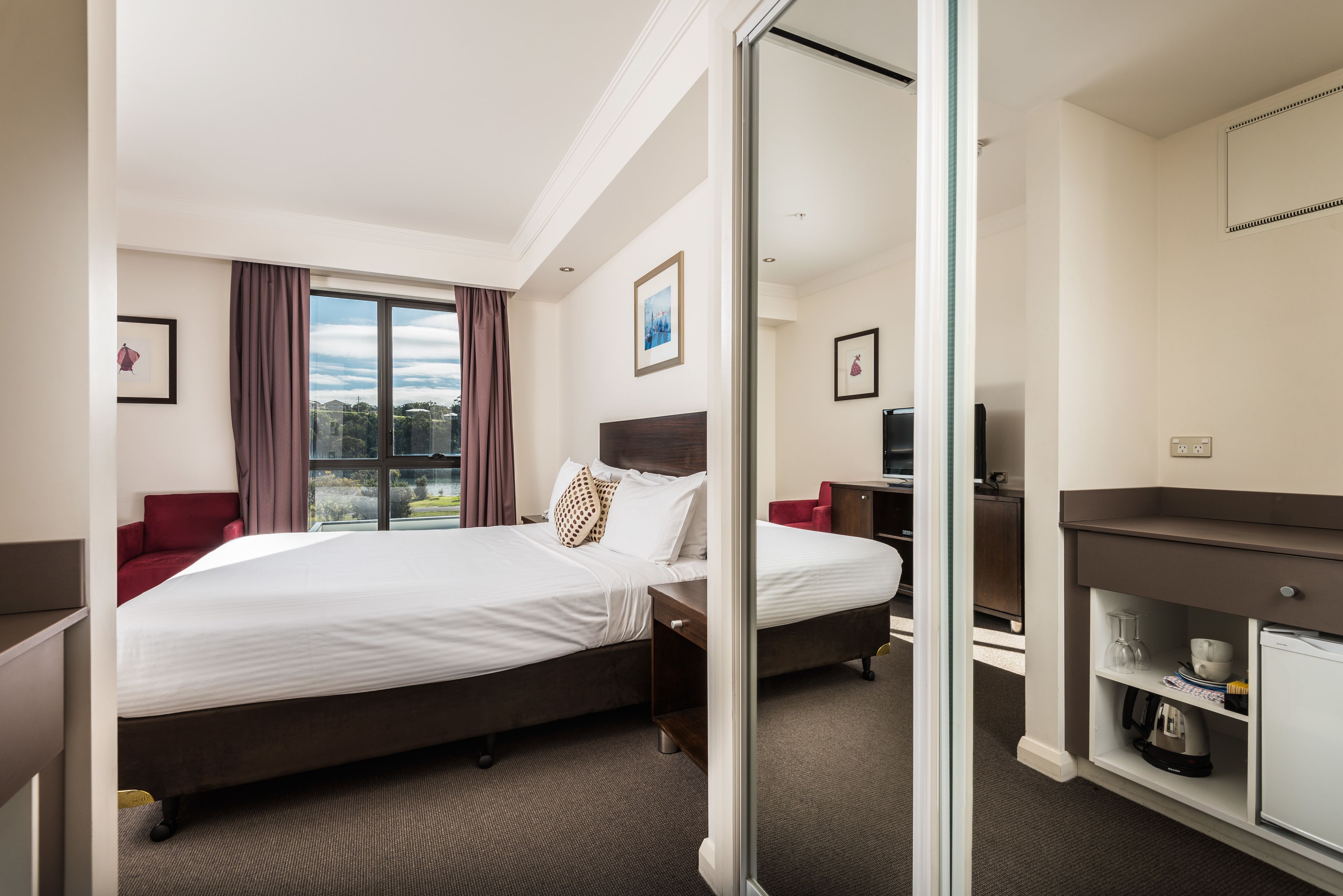 Une chambre d’hôtel avec deux lits, une télévision, un bureau et une kitchenette.