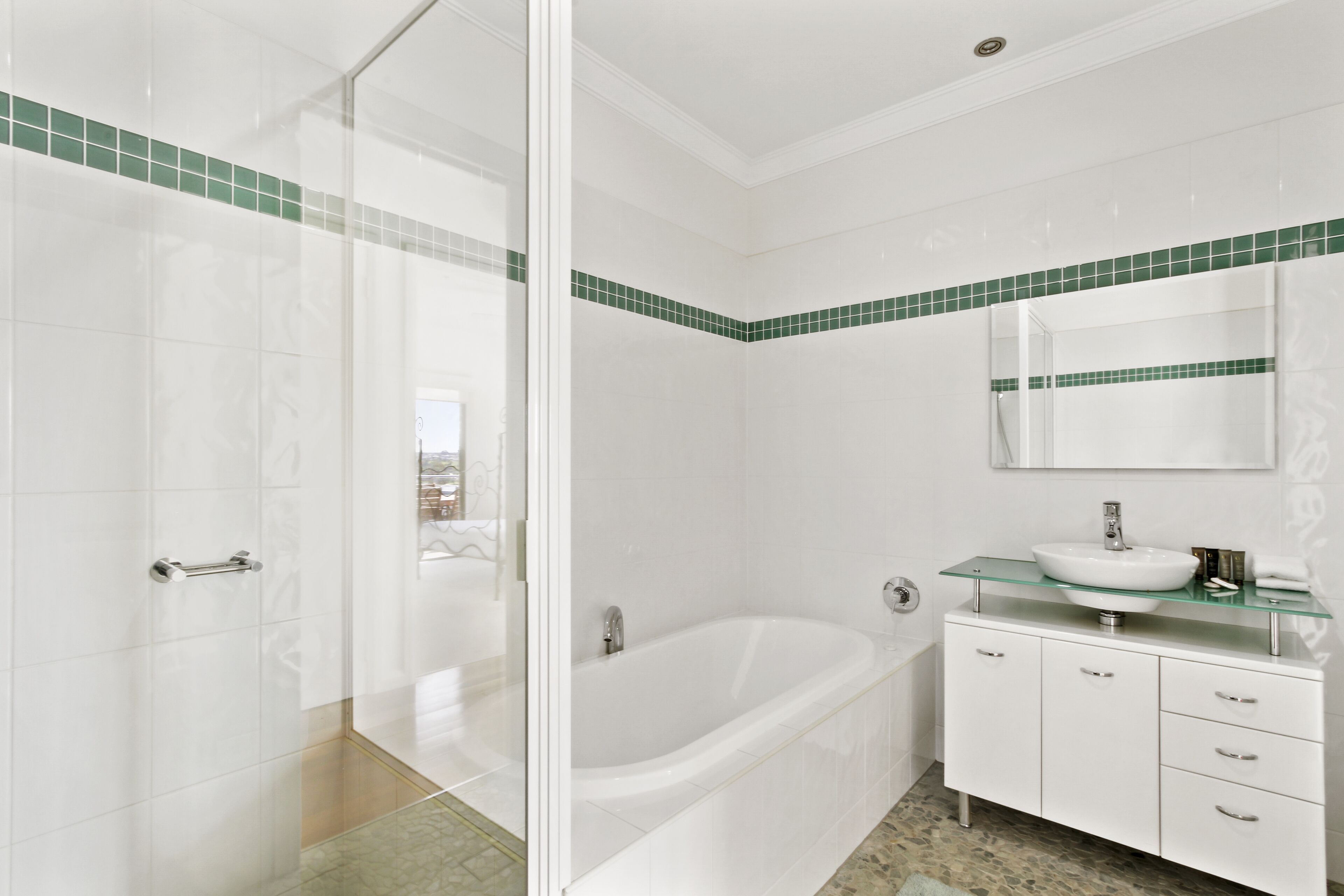 A modern bathroom with a glass shower enclosure, a freestanding bathtub, and a vanity with a glass top.