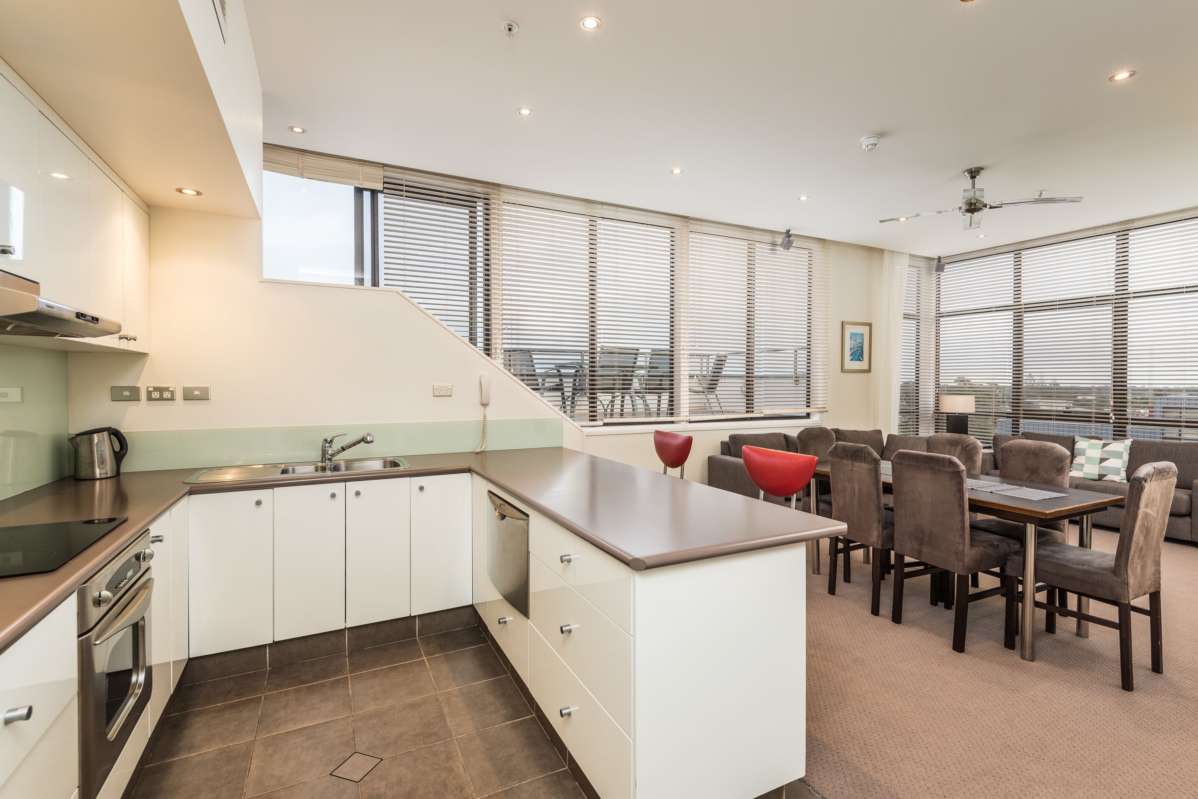 Una cocina moderna con armarios blancos, una isla central y una zona de comedor con una mesa y sillas.