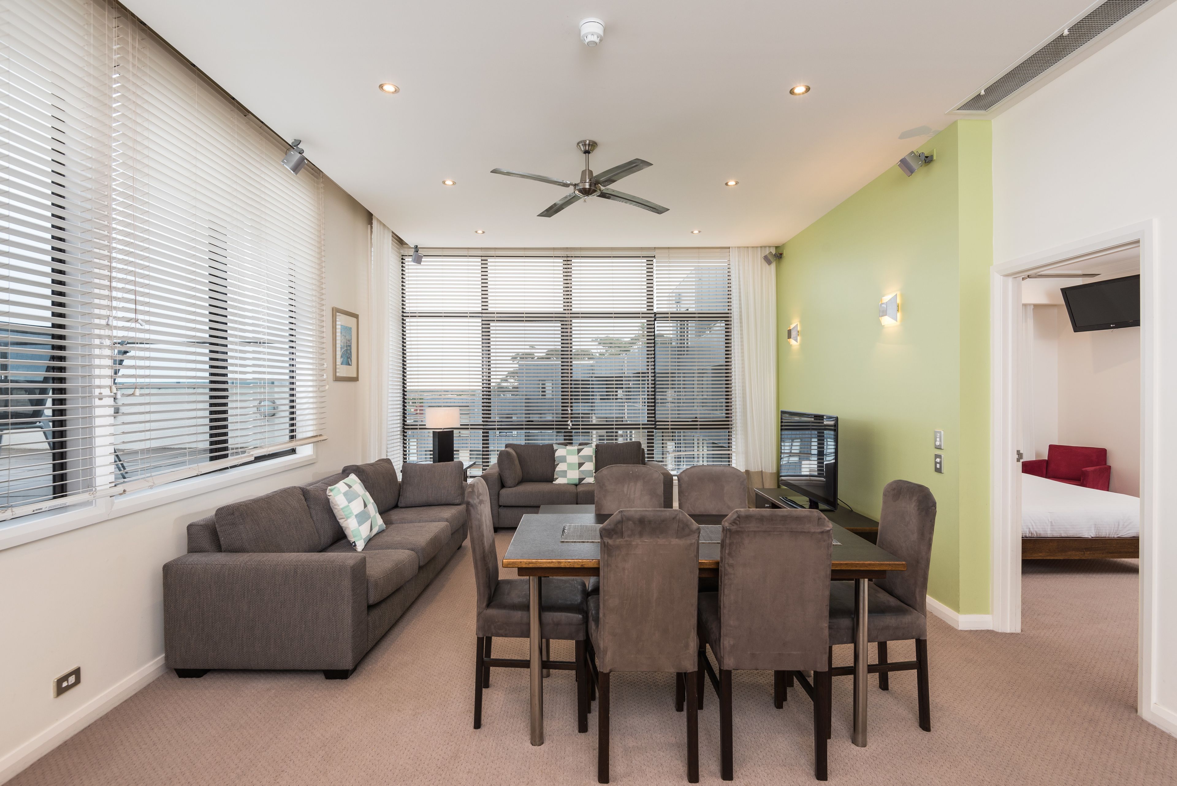 Una sala de estar moderna con comedor, sofá, televisor de pantalla plana y ventilador de techo.