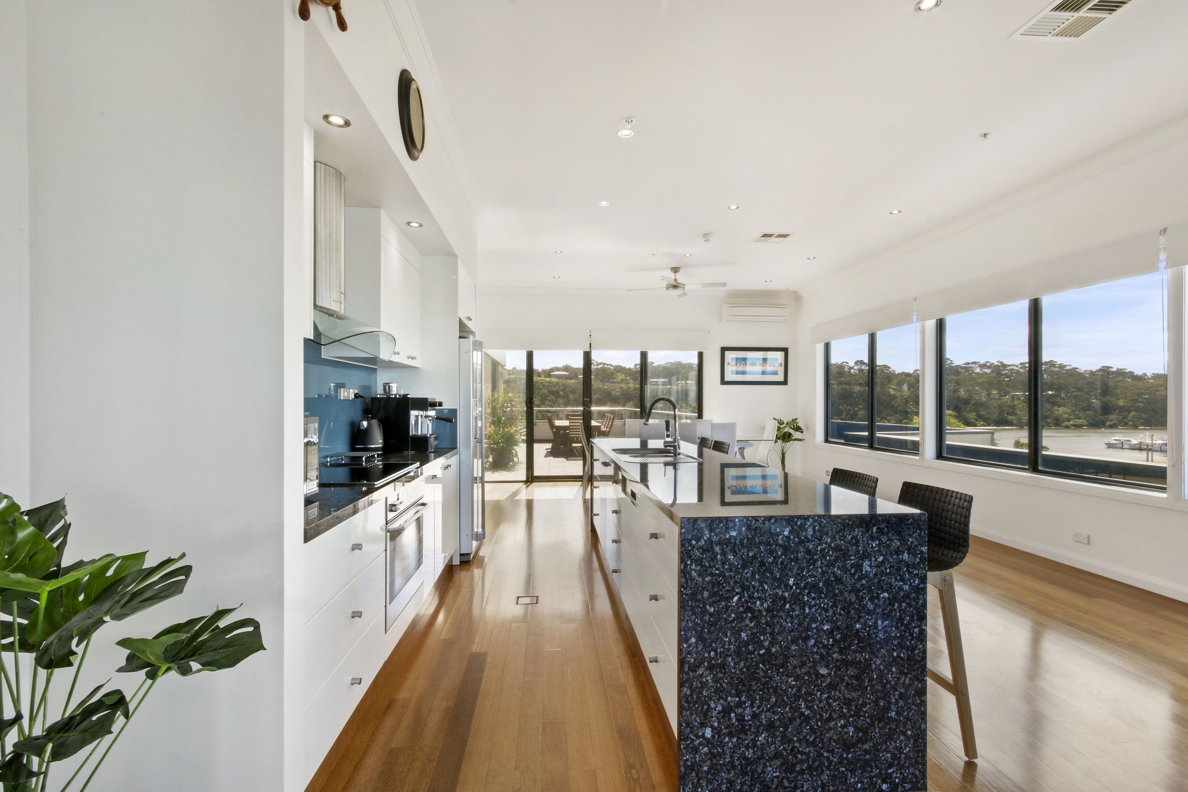 A modern kitchen with a central island, large windows, and a view of the outdoors.