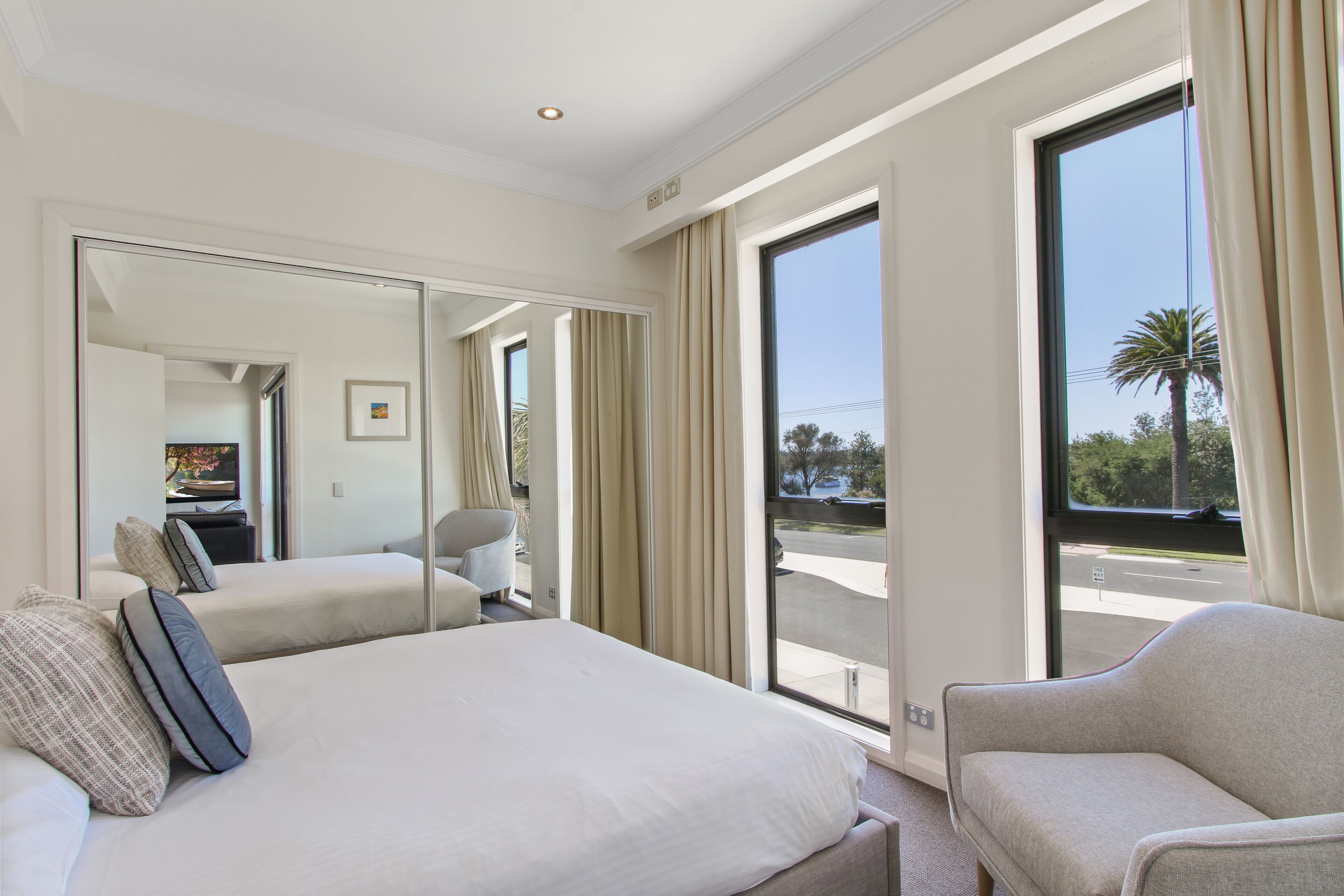 Une chambre d’hôtel avec un grand lit, un coin salon, une grande fenêtre avec des rideaux et une vue sur l’extérieur.