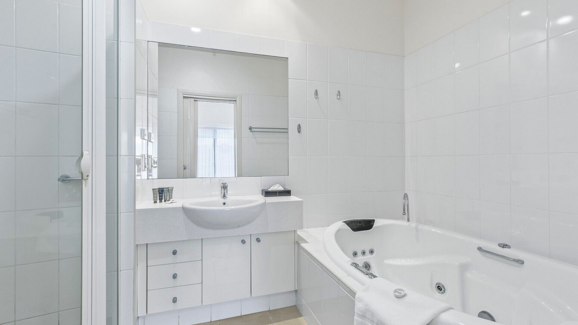Een moderne badkamer met een ruime wastafel, een bad en een spiegel boven de wastafel.