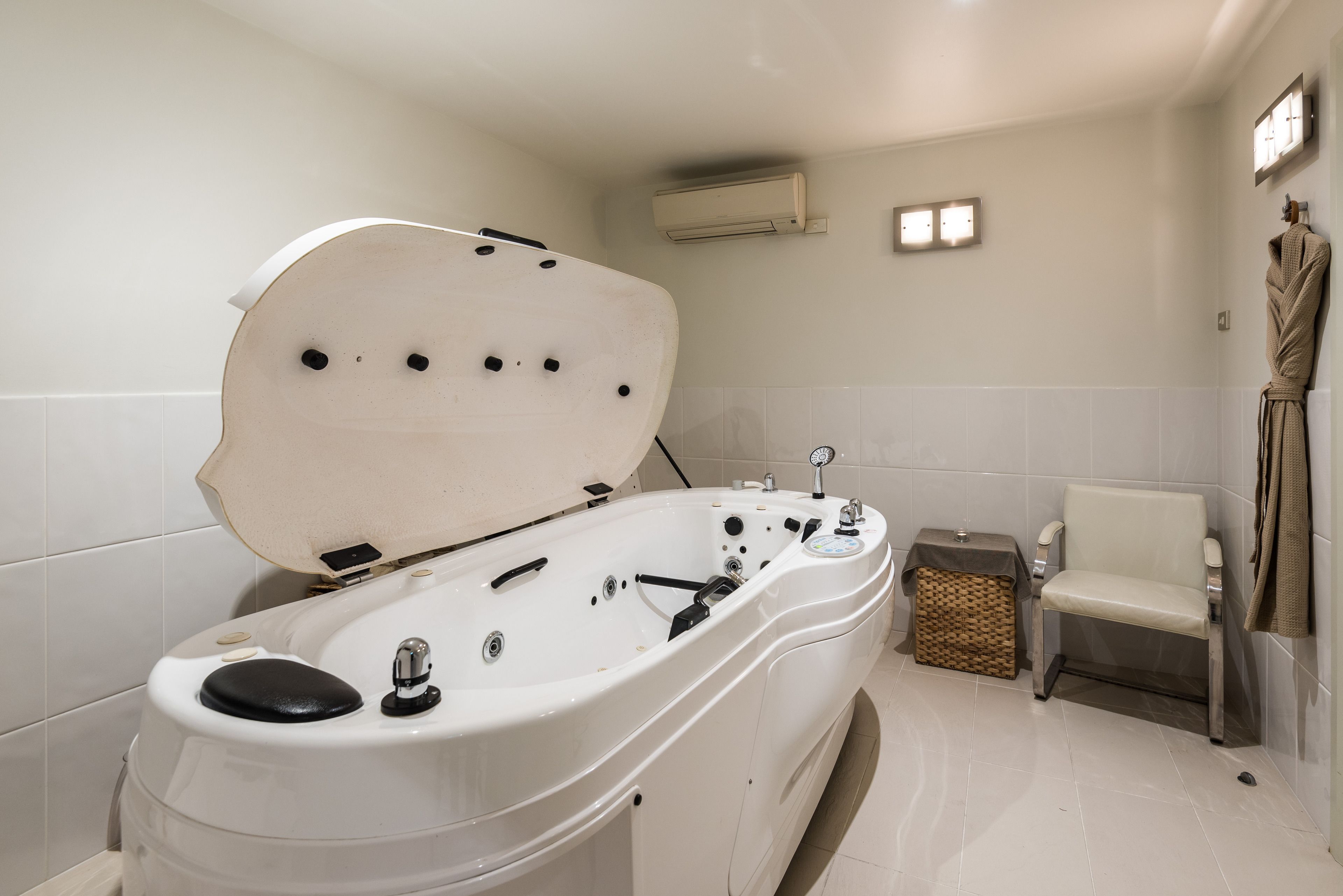 A modern bathroom with a freestanding bathtub, a small table, and a chair.