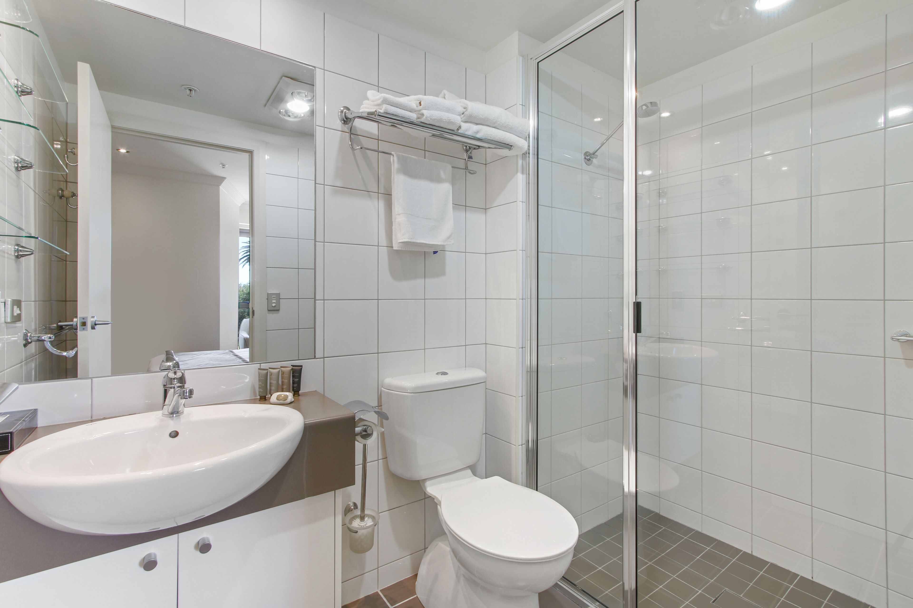 A modern bathroom with a white sink, toilet, and glass shower enclosure.