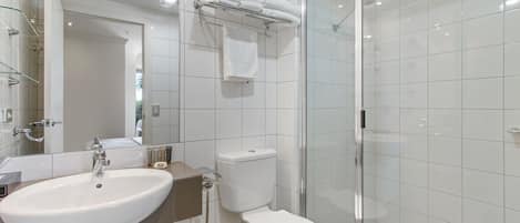 A modern bathroom with a white sink, toilet, and glass shower enclosure.