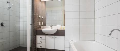 Un baño moderno con cabina de ducha de vidrio, lavamanos blanco y bañera.