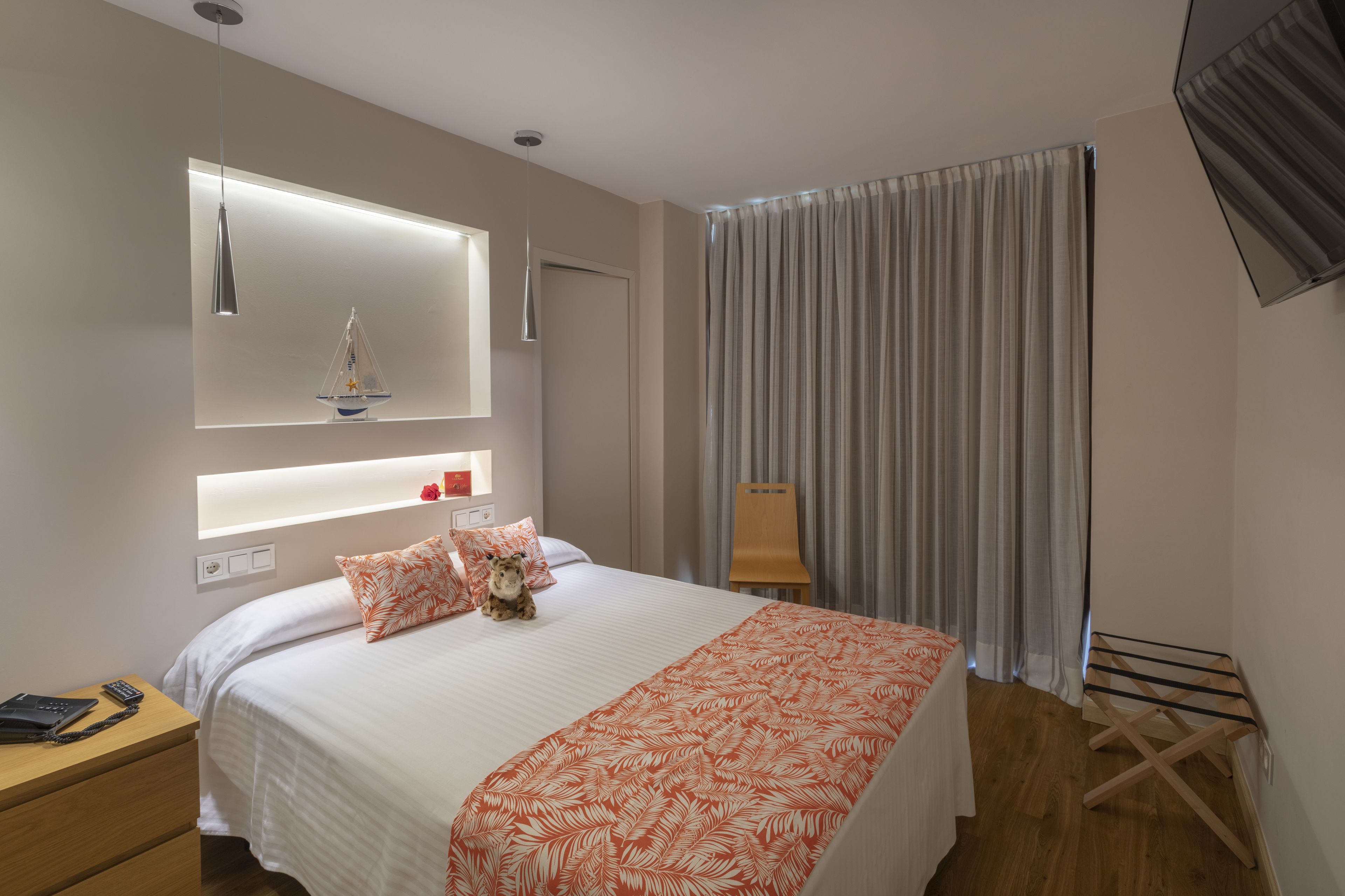A hotel room with a bed, bedside table, lamp, and curtains.