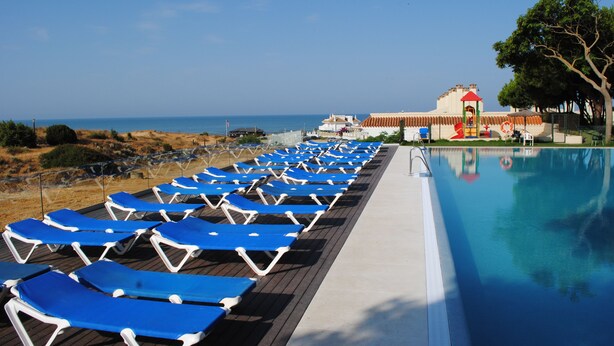 A poolside area with blue lounge chairs and a clear view of the sea. - Gran Hotel del Coto (Almonte)