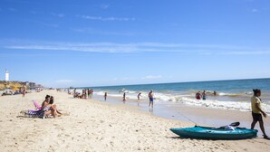 A beach with people, a lighthouse, and a boat on the sand. - Gran Hotel del Coto (Almonte)