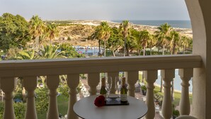 A balcony with a table featuring a bottle of champagne, two glasses, and a rose. The view includes palm trees and a beach. - Gran Hotel del Coto (Almonte)