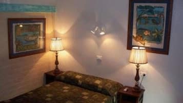 A bedroom with a bed, two bedside lamps, and two framed pictures on the wall.