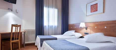 Habitación de hotel con dos camas, un escritorio, una silla, un televisor y una ventana con cortinas.