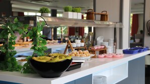 A buffet setup with a variety of food items and a decorative plant. - Pato Amarillo (Punta Umbría)