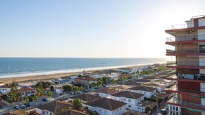 A coastal residential area with houses, a beach, and a large building with balconies. - Pato Amarillo (Punta Umbría)