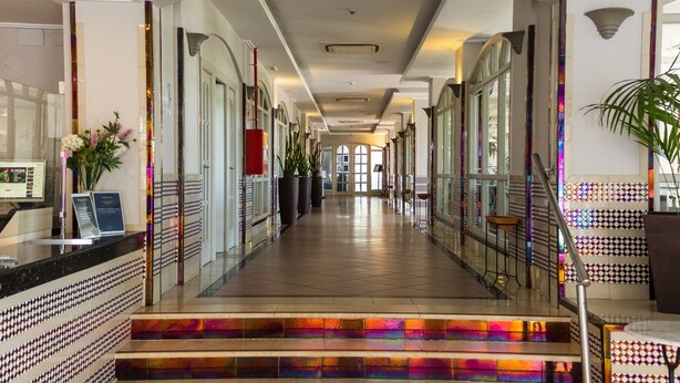 A hotel lobby with a long corridor, a reception desk, and a staircase with colorful steps. - Pato Amarillo (Punta Umbría)