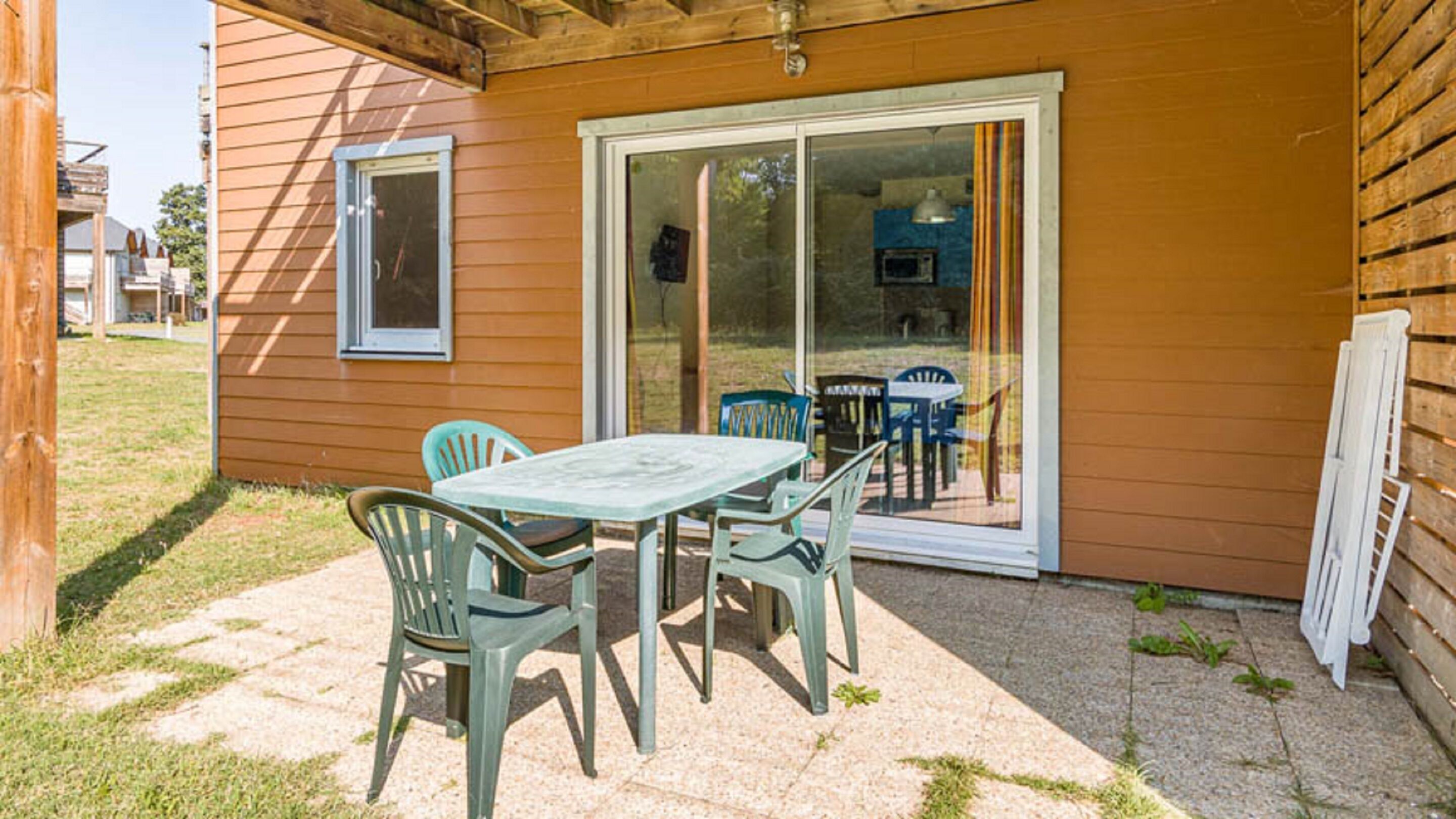 A patio with a table and chairs, a sliding glass door, and a view of the backyard.