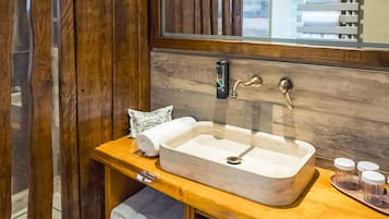 A bathroom with a wooden vanity, a large sink, and a towel dispenser.
