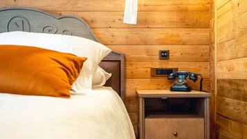 A wooden cabin-style room with a bed, a nightstand, and a telephone.