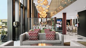 Un hall d'entrée moderne avec un canapé, des coussins à motifs et un luminaire suspendu.