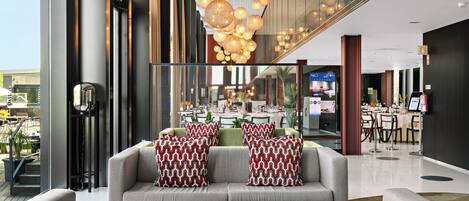 Un hall d'entrée moderne avec un canapé, des coussins à motifs et un luminaire suspendu.