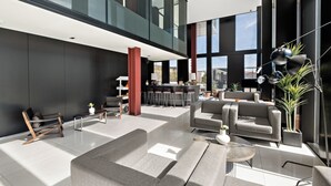 Un hall d’entrée spacieux, doté de meubles modernes, d’un bar et de grandes fenêtres offrant une vue sur la ville.