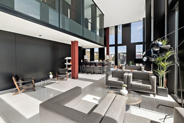 Un vestíbulo amplio con mobiliario moderno, una zona de bar y grandes ventanales con vistas a la ciudad.
