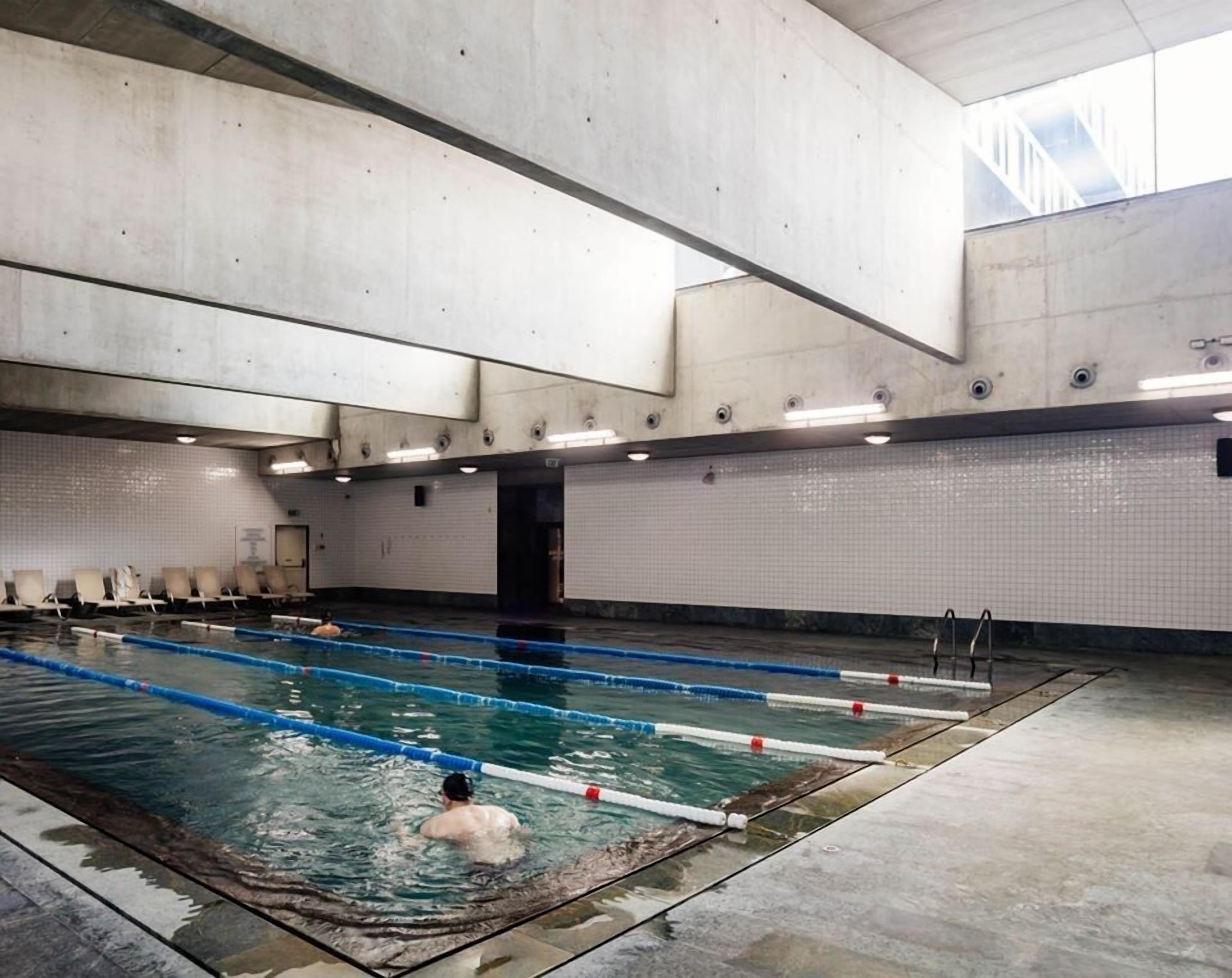 Una piscina interior con varias pistas, pared de azulejos y techo alto.