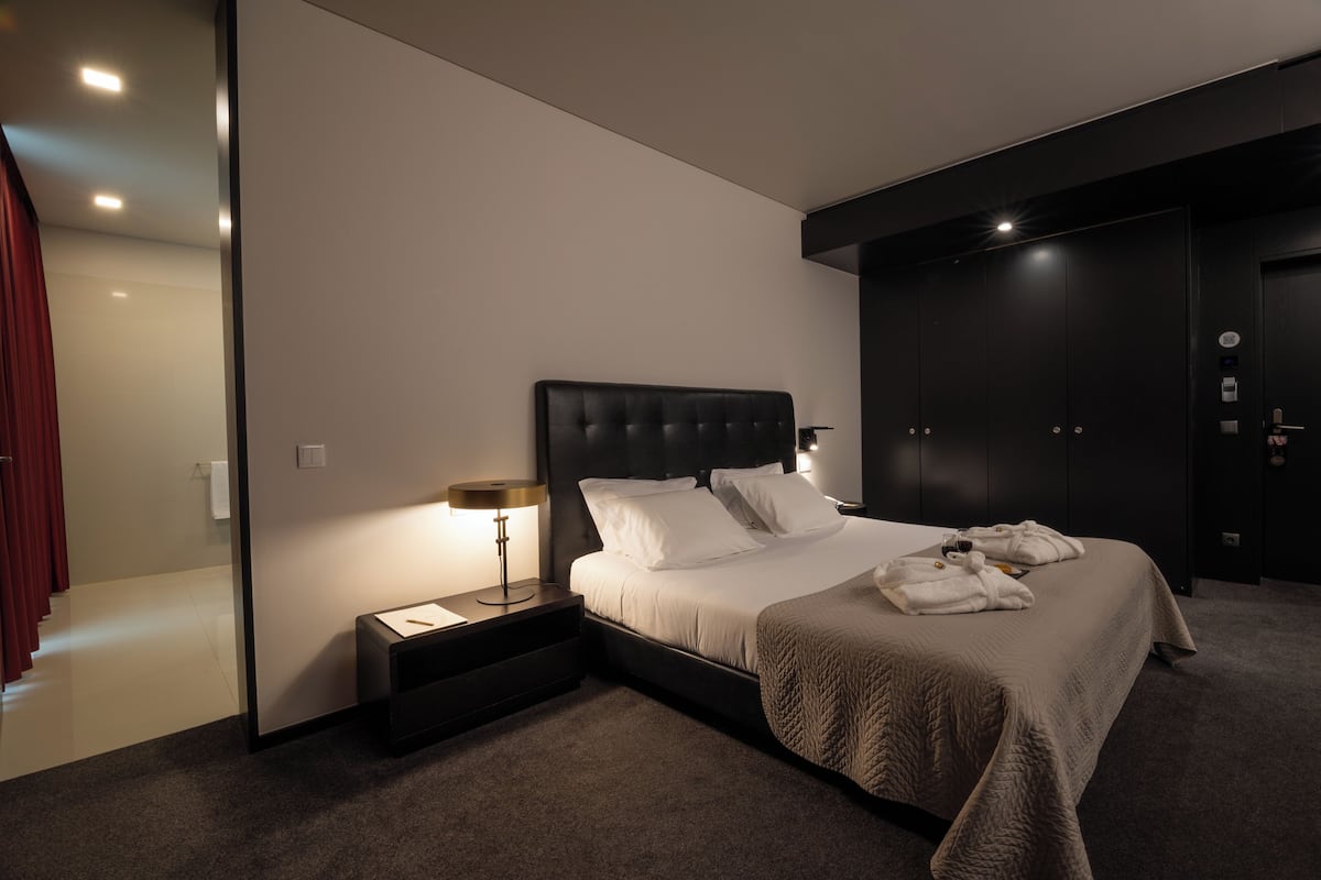 Een moderne hotelkamer met een groot bed, een nachtkastje met lamp en een kledingkast.