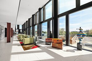 Un hall d’entrée spacieux, doté de grandes fenêtres, de mobilier moderne et d’une sculpture originale.