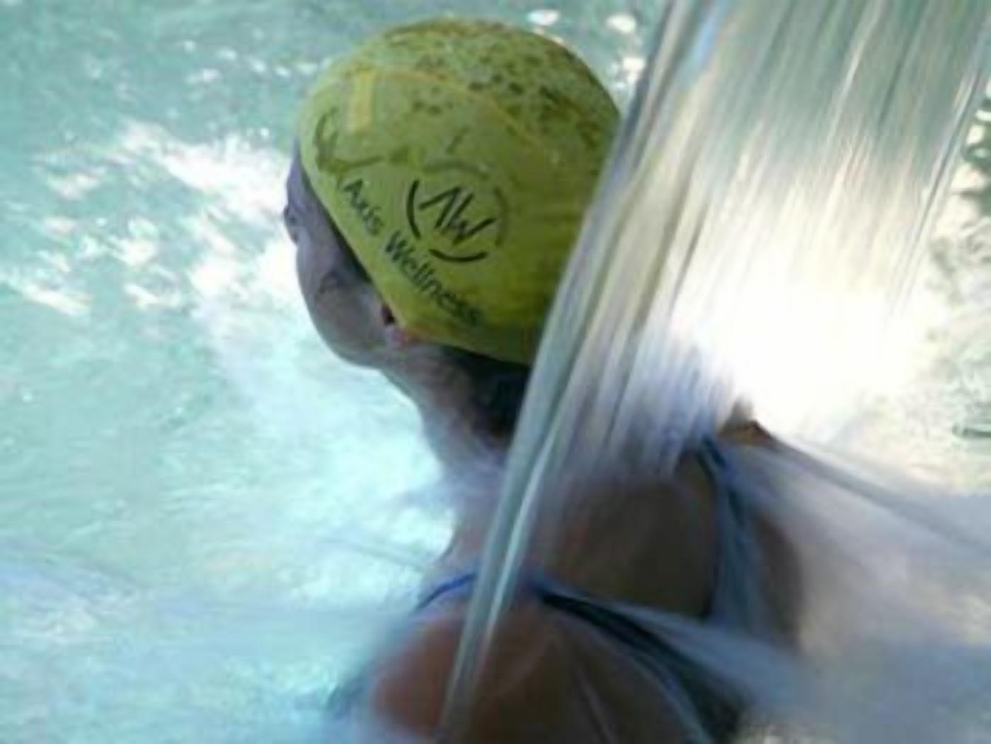 A person wearing a yellow swim cap with a logo, in a pool.