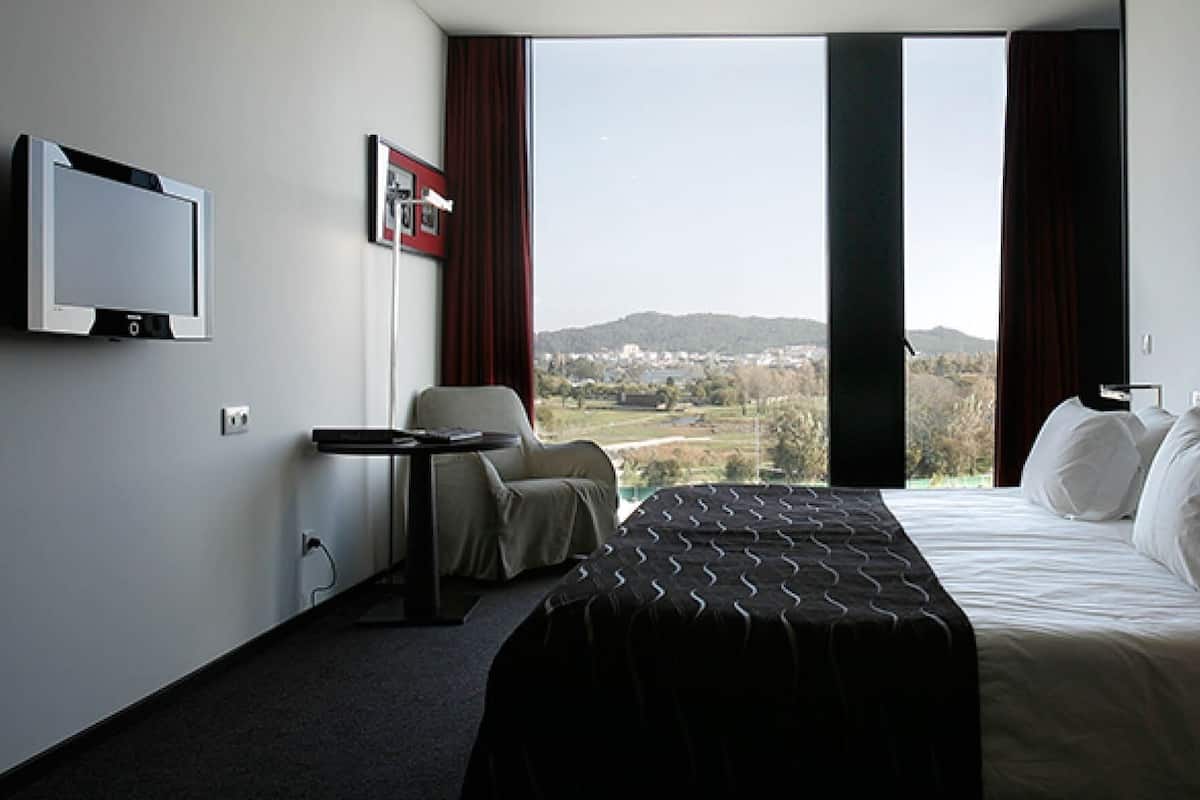 Een hotelkamer met een bed, een televisie, een stoel en uitzicht op de omgeving.