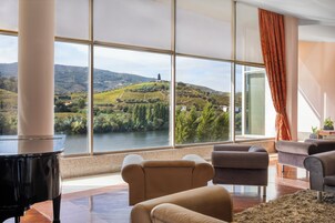 A spacious living room with a large window offering a view of a river and hills.
