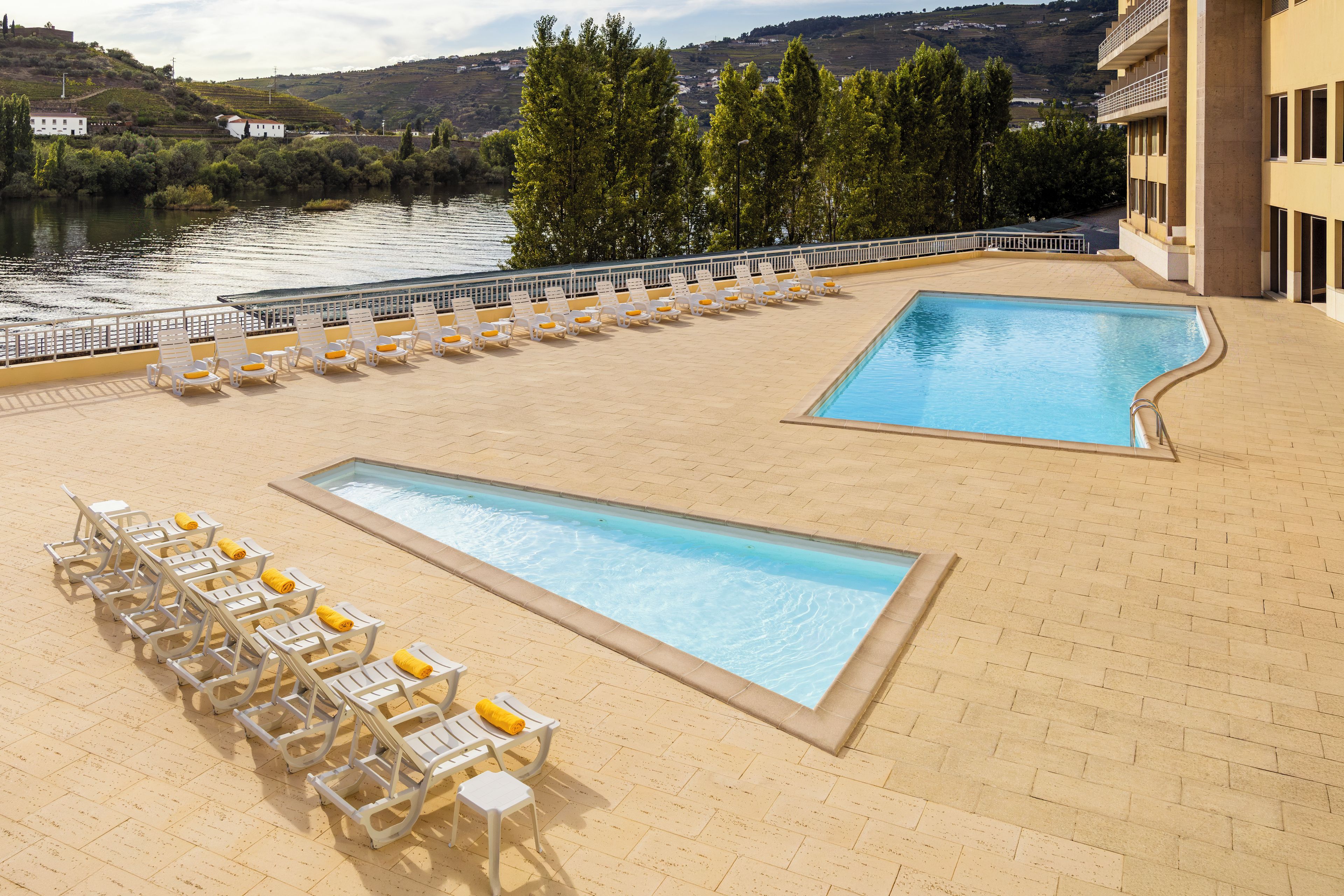 Zona de piscina con sillones de descanso y vistas a un río.