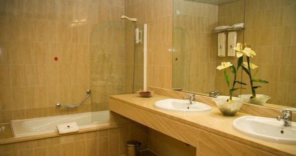 A bathroom with two sinks, a bathtub, and a shower.